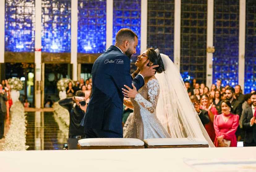 Intimate ceremony kiss at altar with stunning blue stained glass windows and wedding guests
