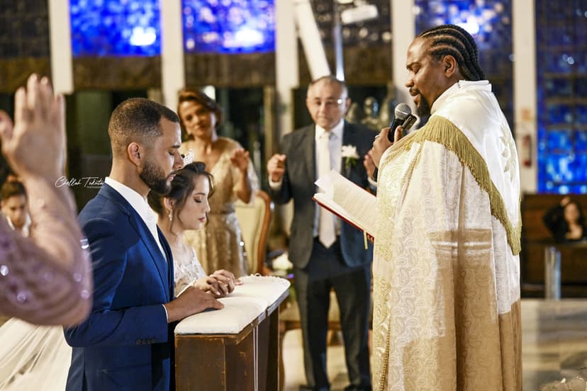 Groom signing wedding documents while officiant in white and gold vestments speaks