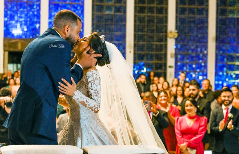 Romantic ceremony kiss with blue stained glass backdrop and wedding guests watching