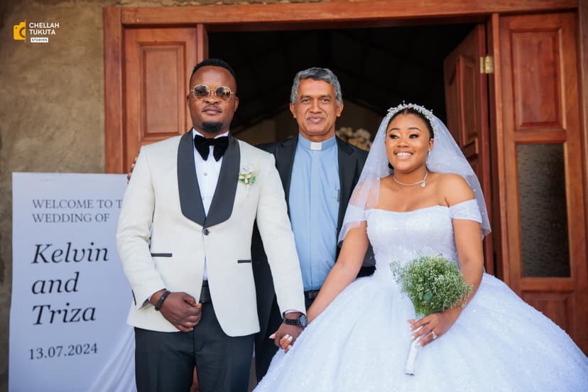 Formal wedding photo with couple and officiant outside church