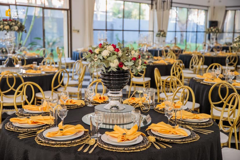 Elegant reception table setup with gold chairs and black tablecloths