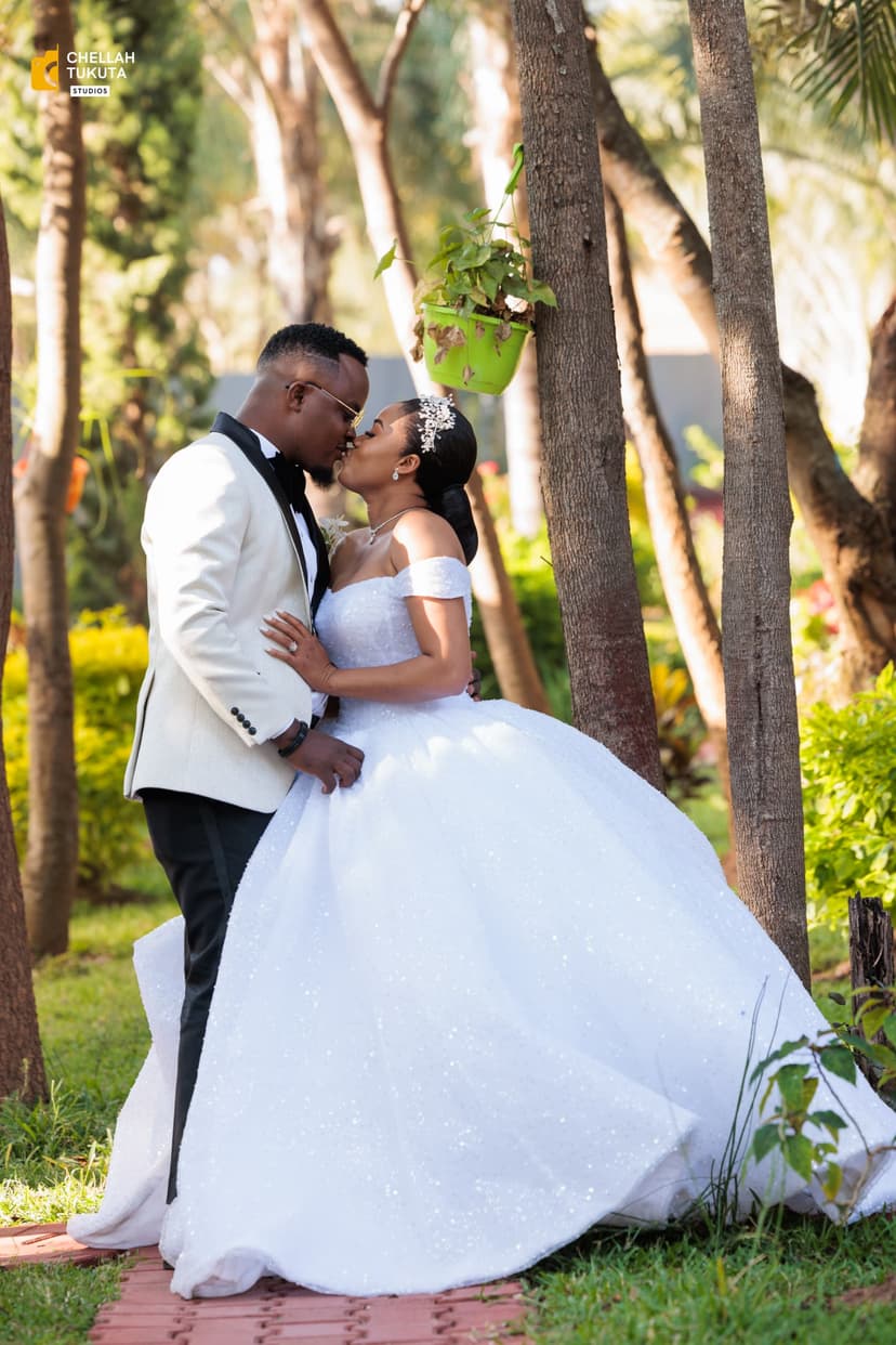 Romantic couple kiss in garden setting with white wedding attire