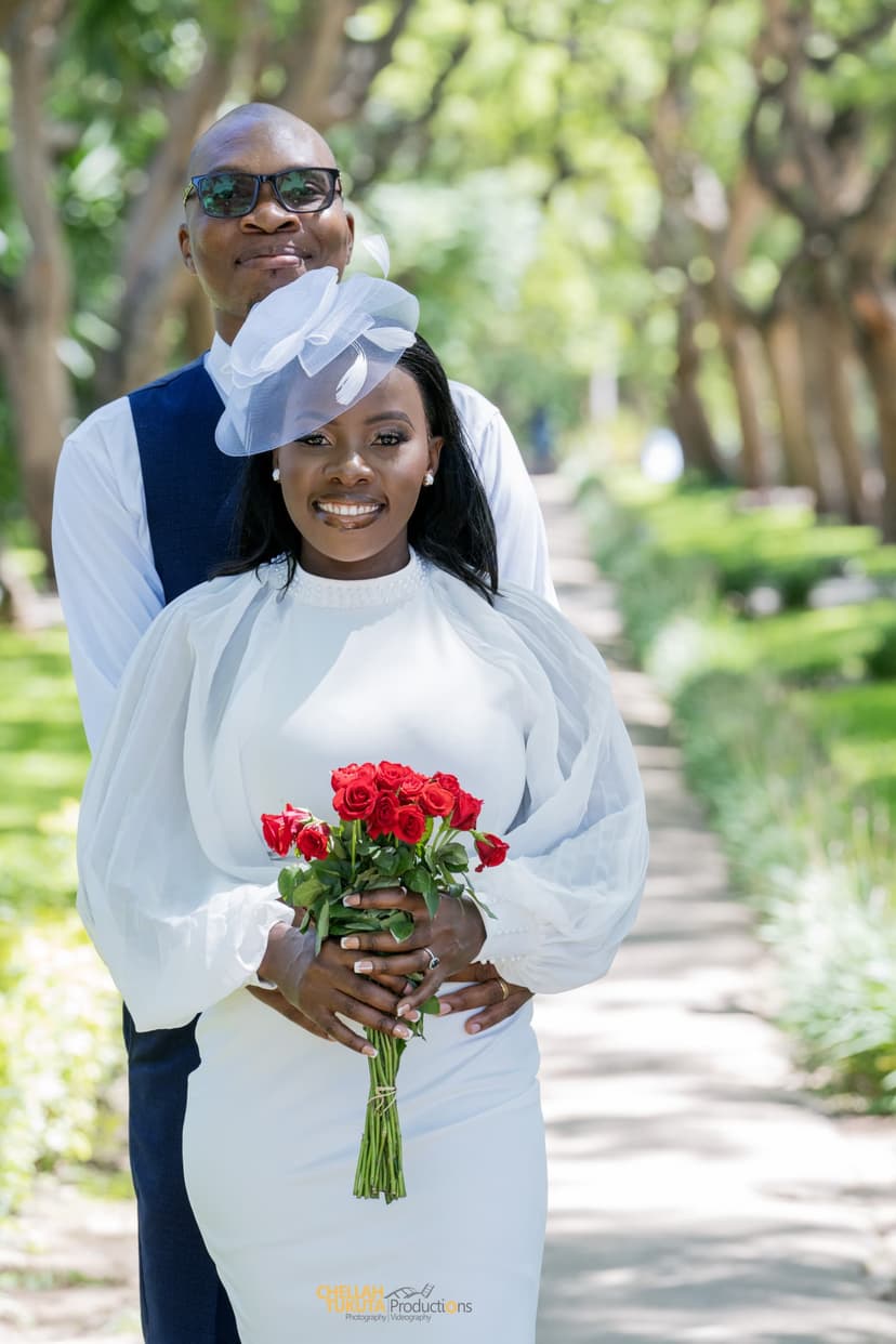 Romantic couple portrait in tree-lined path with red roses