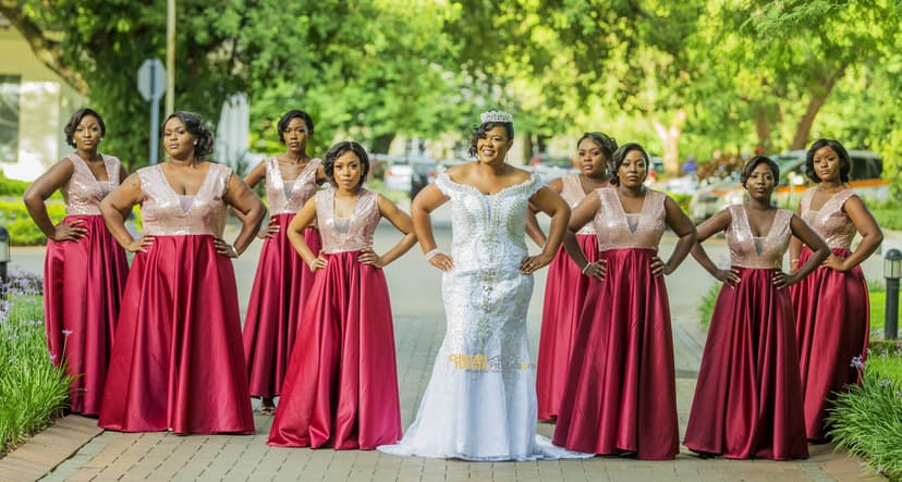Bride in sparkly off-shoulder gown with tiara surrounded by bridesmaids in burgundy dresses