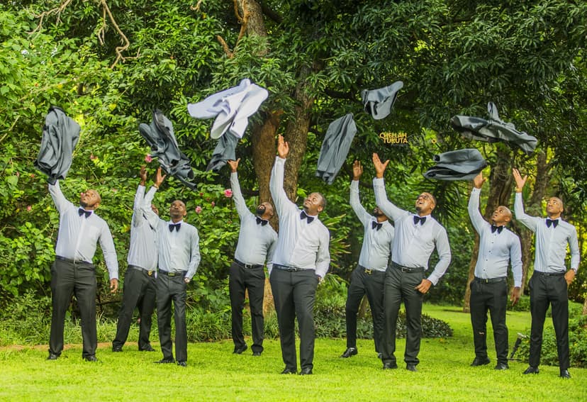 Fun groomsmen photo throwing suit jackets in the air in garden setting