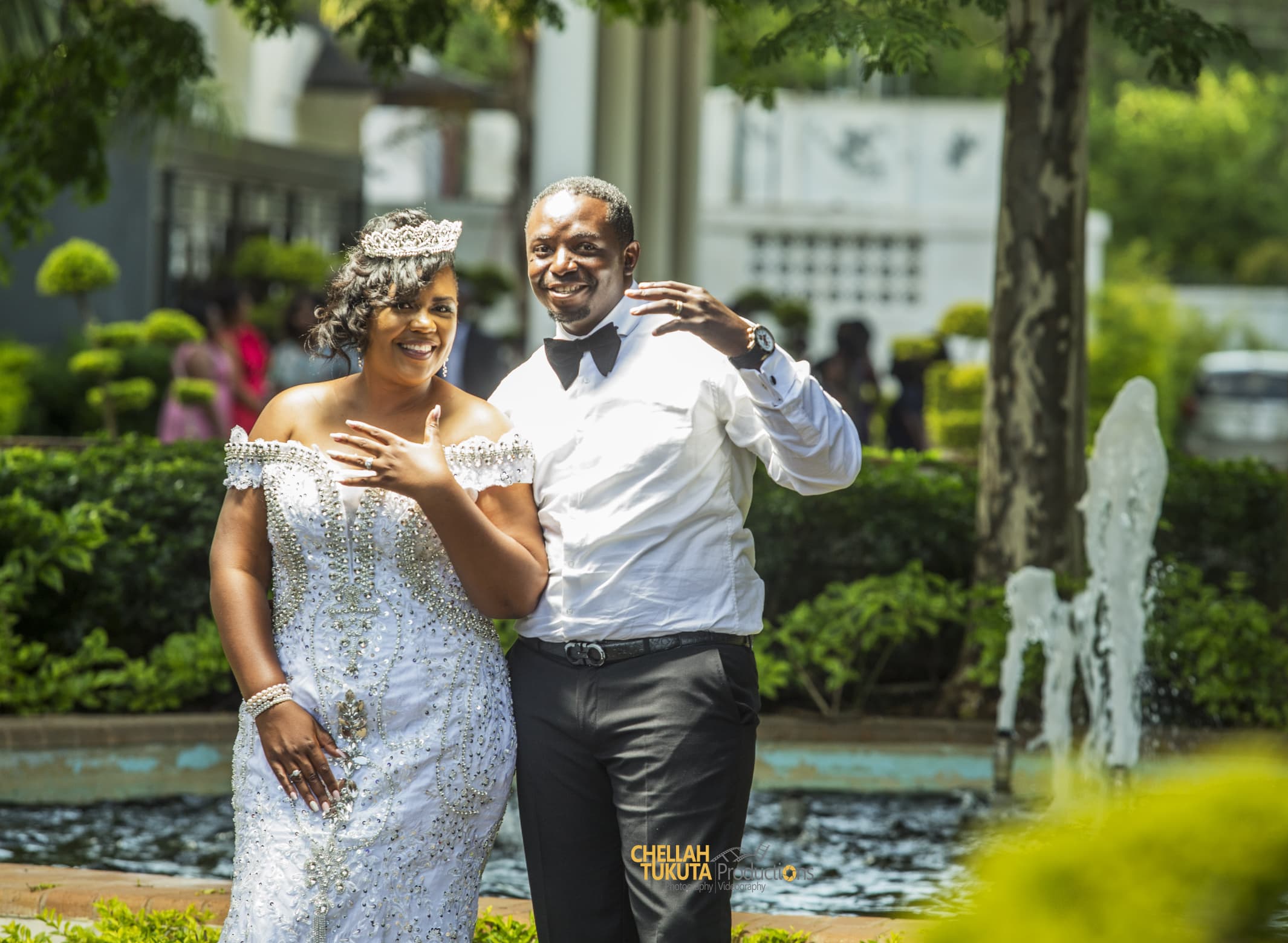 Joyful celebration by fountain - couple laughing in sparkly attire with tiara