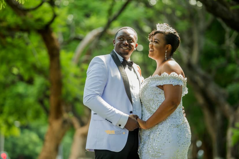 Happy couple portrait laughing in garden - bride in sparkly gown with tiara, groom in white jacket