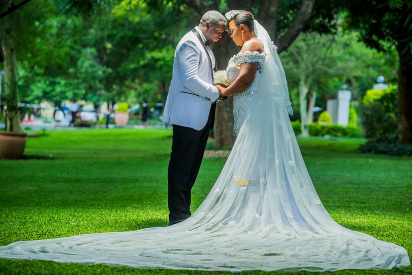 Intimate romantic moment - couple forehead to forehead in park, bride with long veil
